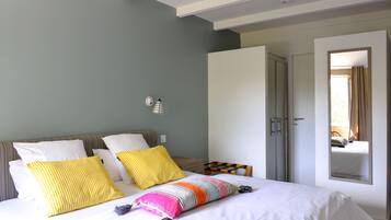 Una camera da letto con un letto, cuscini, un comodino, un armadio e uno specchio.