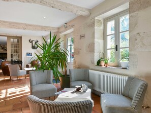 A room with houndstooth patterned furniture, a large potted plant, and a radiator. - Logis Hôtels - Hôtel et Restaurant La Ferme de Flaran (Maignaut-Tauzia)