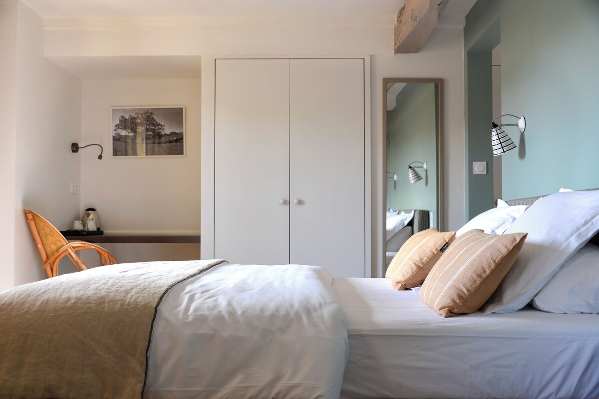 A bedroom with a bed, a chair, a wardrobe, and a wall-mounted lamp.