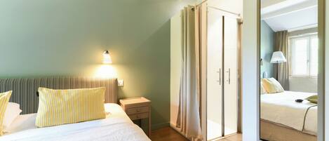 A hotel room with a bed, bedside table, lamp, and a sliding door closet.