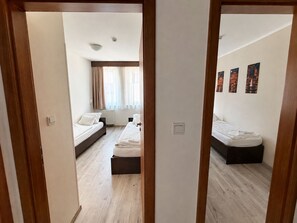 Een hotelkamer met twee bedden, een raam met gordijnen en een wand met ingelijste foto's.