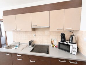 Een moderne keuken met een inbouwfornuis, een koffiezetapparaat, een magnetron en een broodrooster.