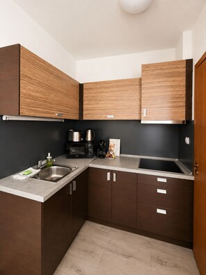 A modern kitchen with dark wood cabinets, stainless steel appliances, and a light-colored countertop. - Prater Residence (Budapest)