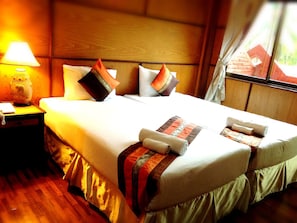A neatly made bed with pillows and a blanket, a bedside lamp, and a wooden headboard. - Jaroenrat Resort (Samut Songkhram)