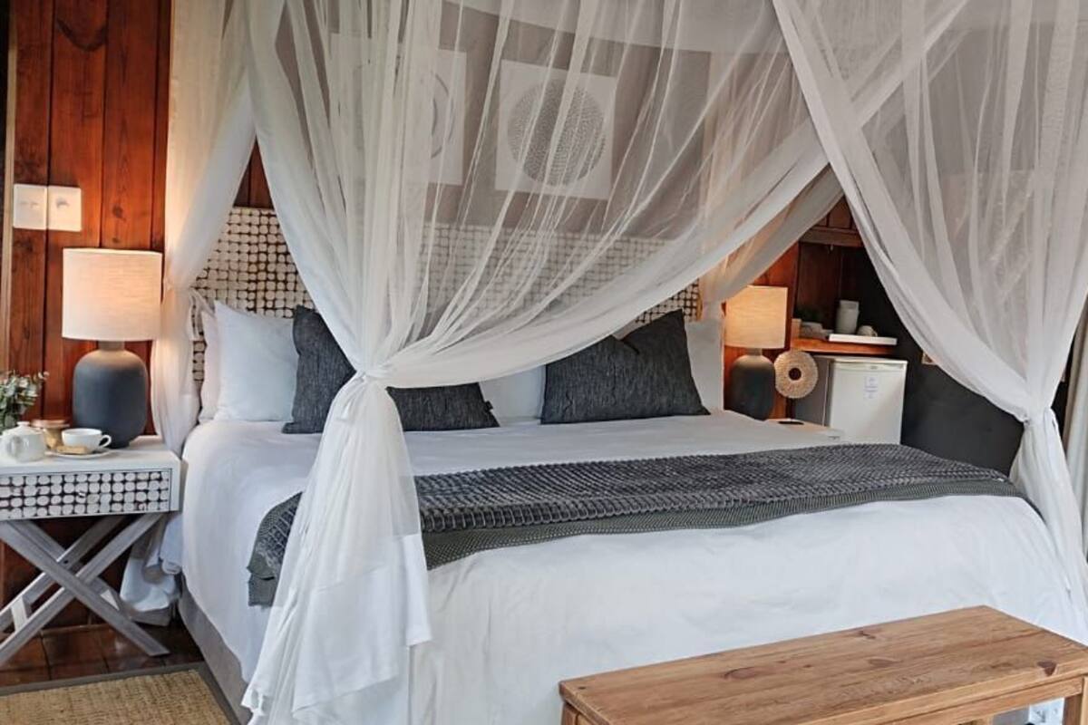 A bedroom with a canopy bed, bedside tables, a nightstand, and a wooden bench.