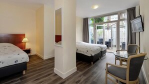 A hotel room with a bed, a desk, and a chair. There is a window with curtains and a view of the outside. - Hotel Bor Scheveningen (The Hague)