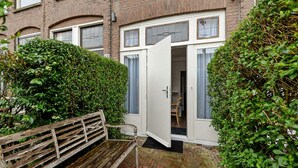 A residential building with a front door open, revealing a room with a chair and a small table. - Hotel Bor Scheveningen (The Hague)