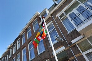 A flagpole with a flag, a sign reading "HOTEL", and a brick building with multiple windows and balconies. - Hotel Bor Scheveningen (The Hague)