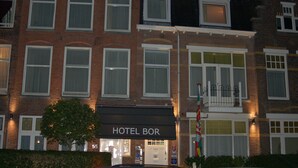 A hotel named "HOTEL BOR" with a traditional brick facade, multiple windows, and a well-lit entrance.
