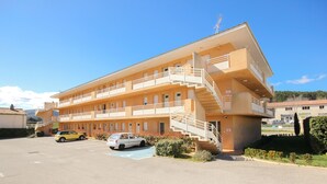 Un hôtel à plusieurs étages, doté de balcons, d’un parking et d’un escalier menant aux étages supérieurs.