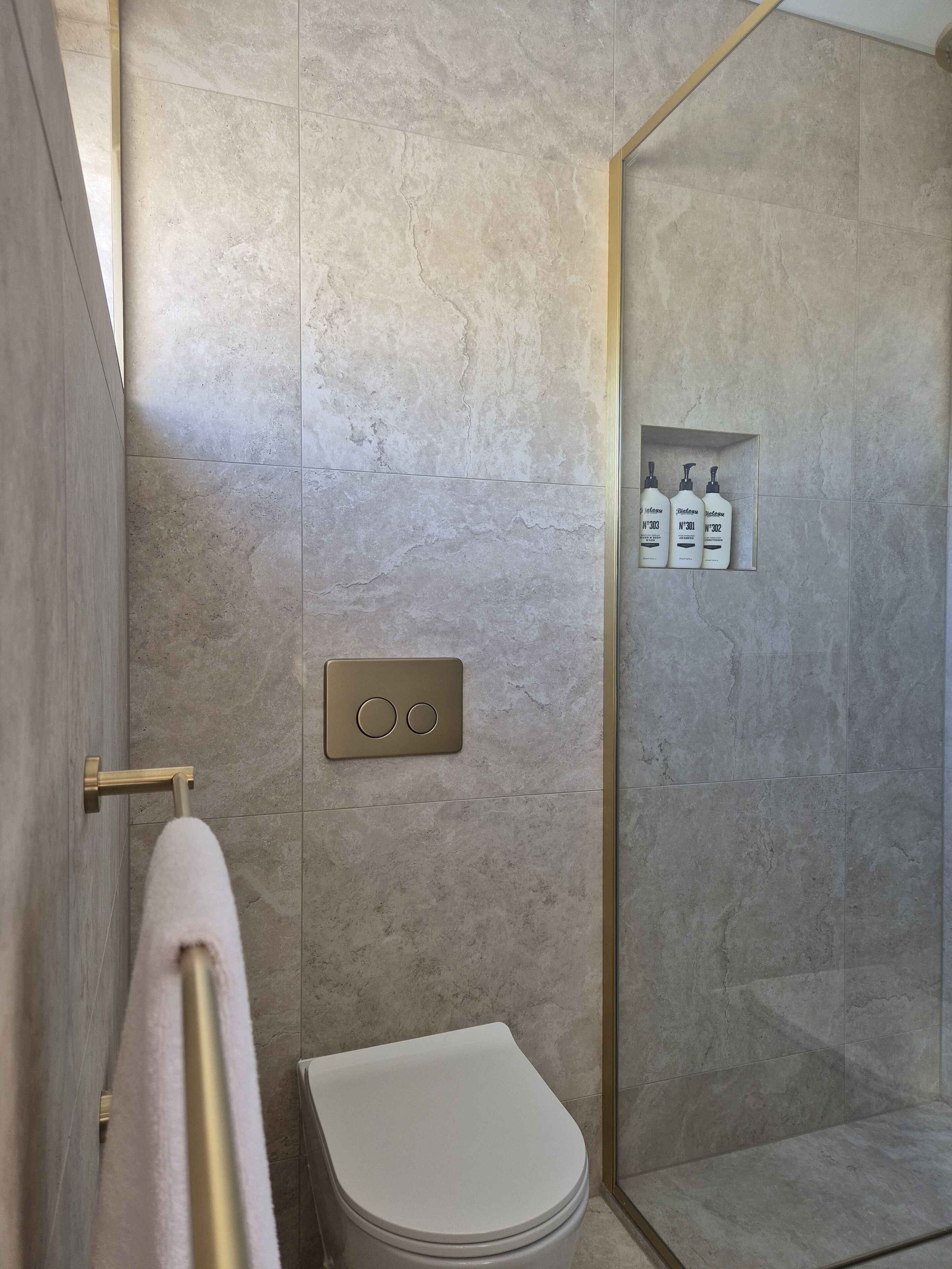 Ein modernes Badezimmer mit Toilette, Handtuchhalter und Duschbereich.