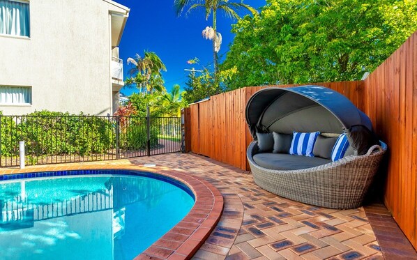 Una piscina al aire libre, sillones reclinables de piscina