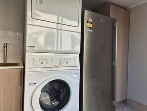 A compact laundry area with a washing machine and a refrigerator.