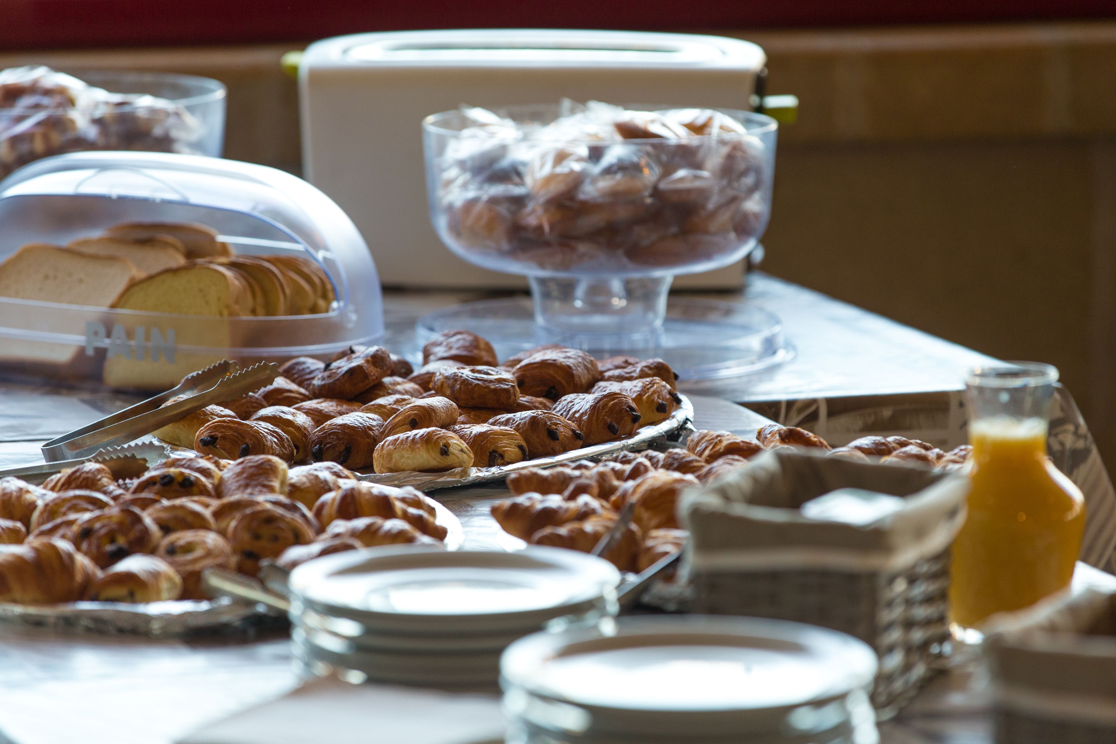 A breakfast buffet with various pastries and a glass of orange juice.
