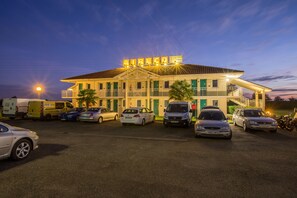 A hotel with a sign reading "AIRECO" and multiple cars parked in front.