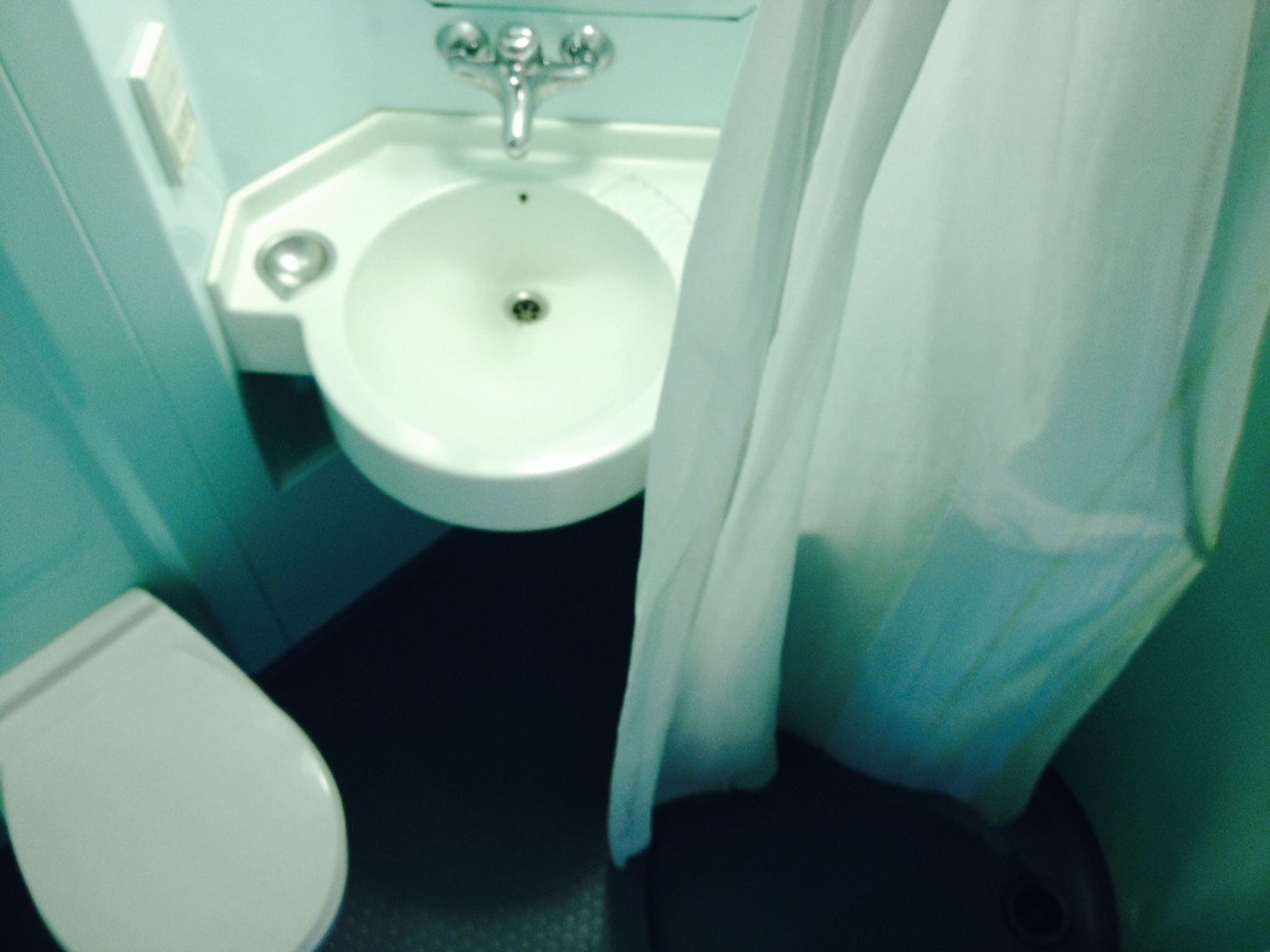 Un baño pequeño con un lavamanos blanco, un inodoro y un suelo oscuro.