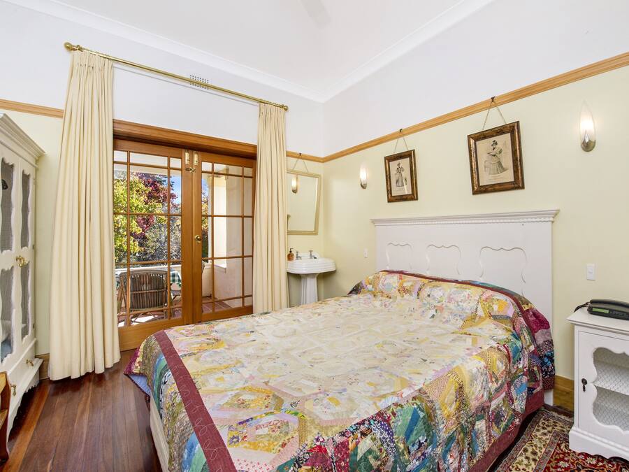 Un dormitorio con una cama grande, una mesita de noche, una ventana con cortinas y vistas al exterior.
