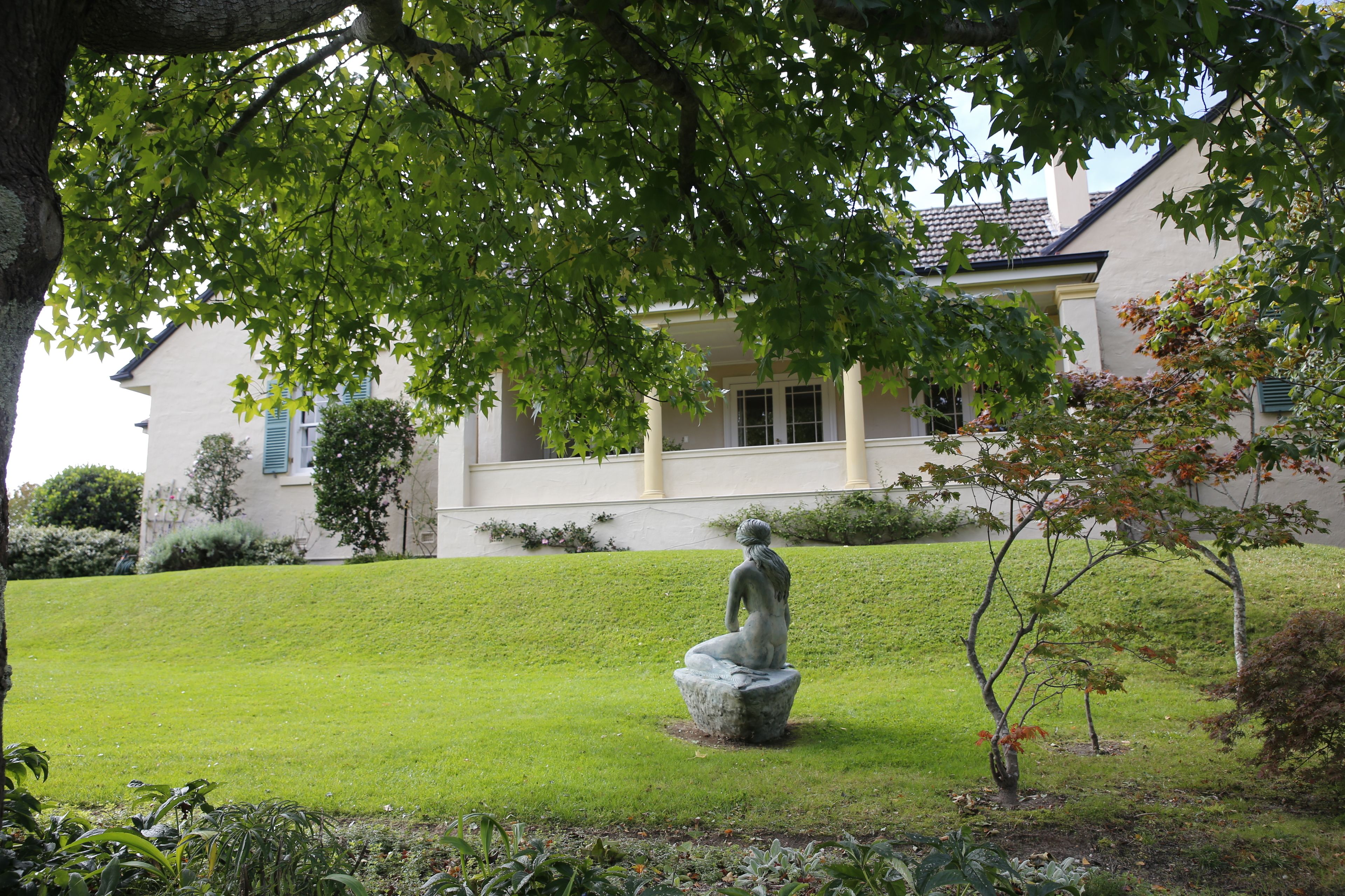 Una estatua en un jardín, con una casa al fondo.