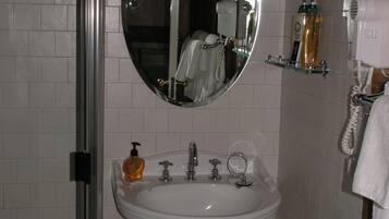 A bathroom with a white sink, a mirror, a hand dryer, and a soap dispenser.