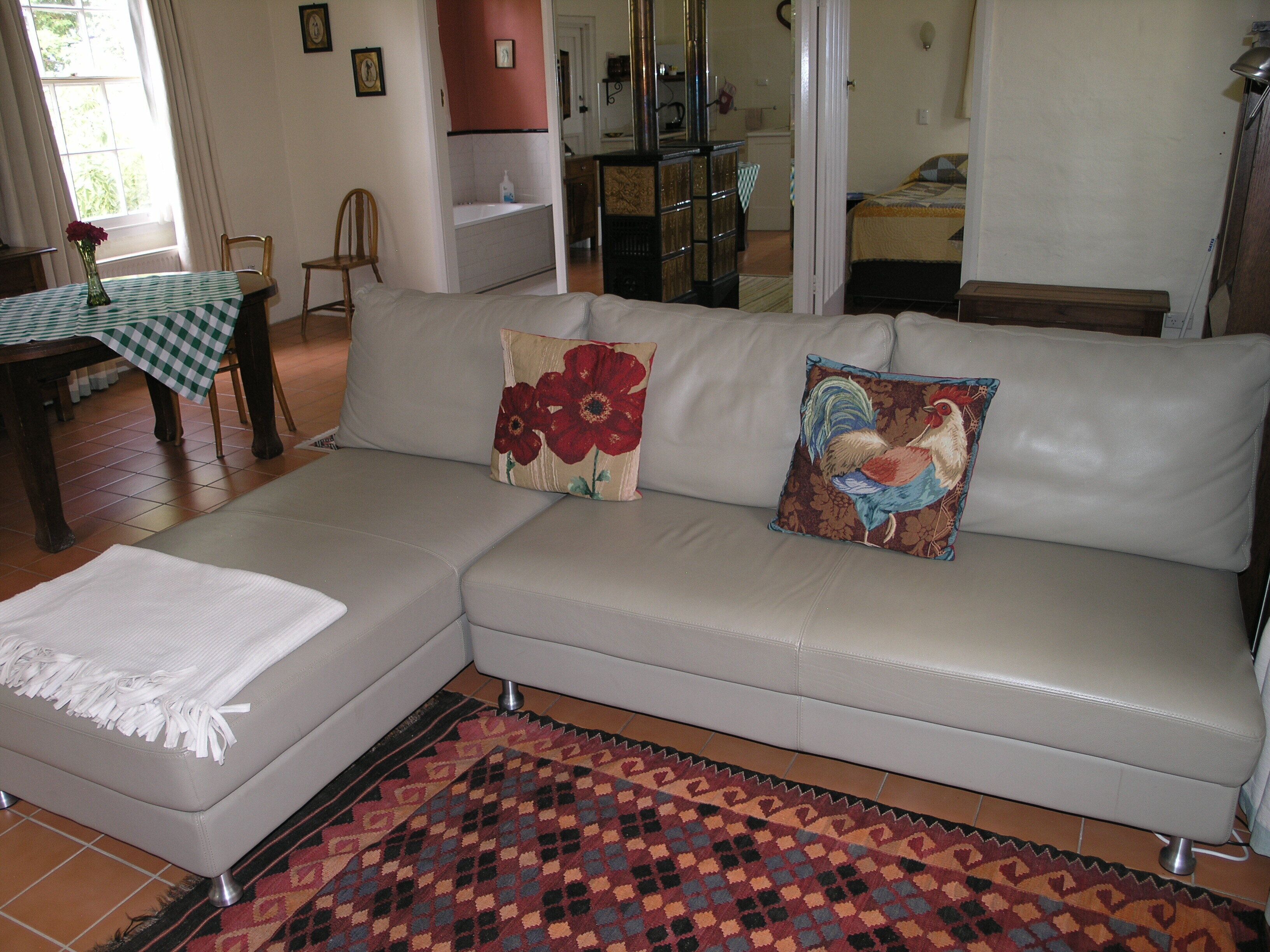 Una sala de estar con un sofá, un tapete estampado y una mesa con mantel a cuadros.
