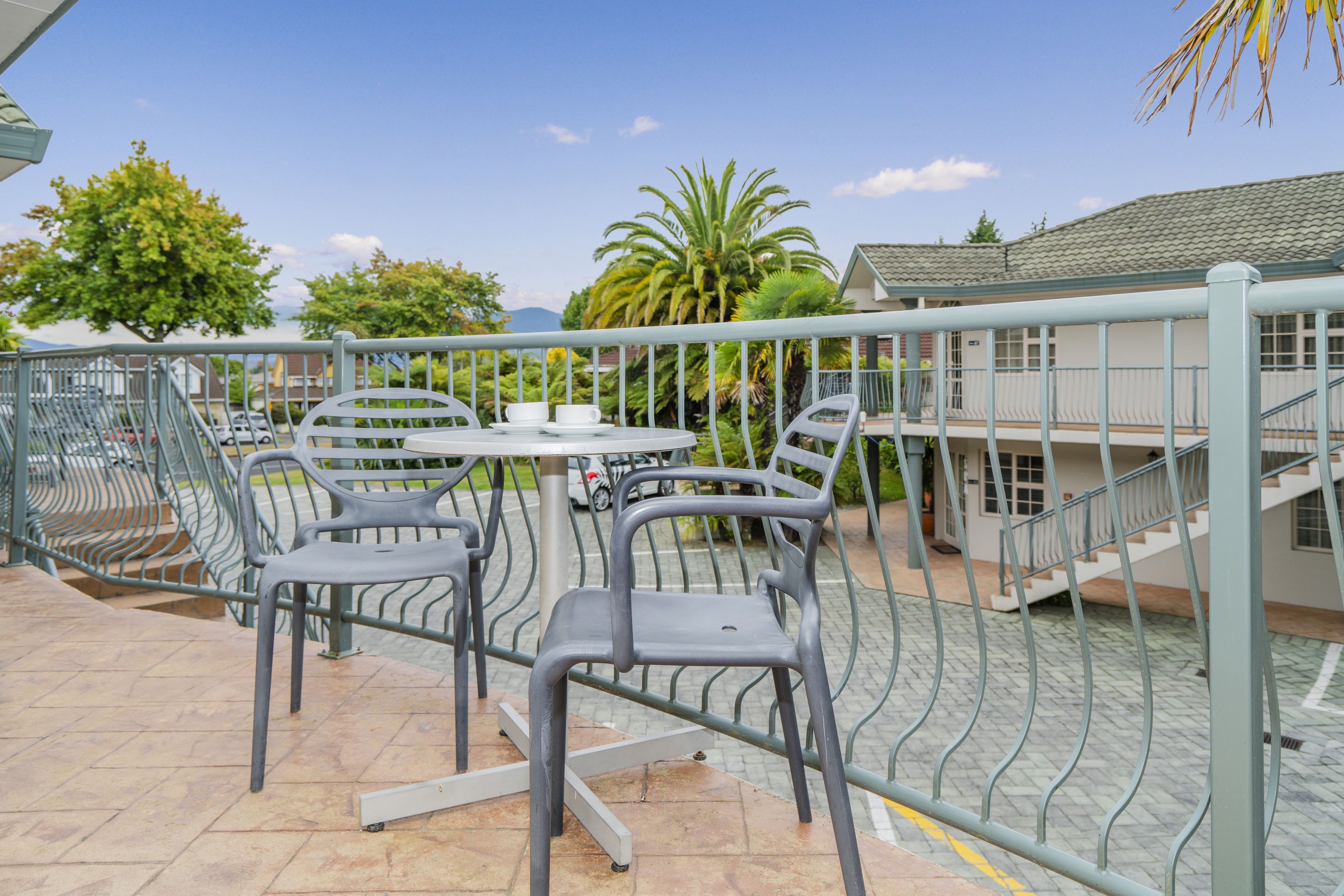 An outdoor patio area with metal chairs and tables, surrounded by a metal fence.