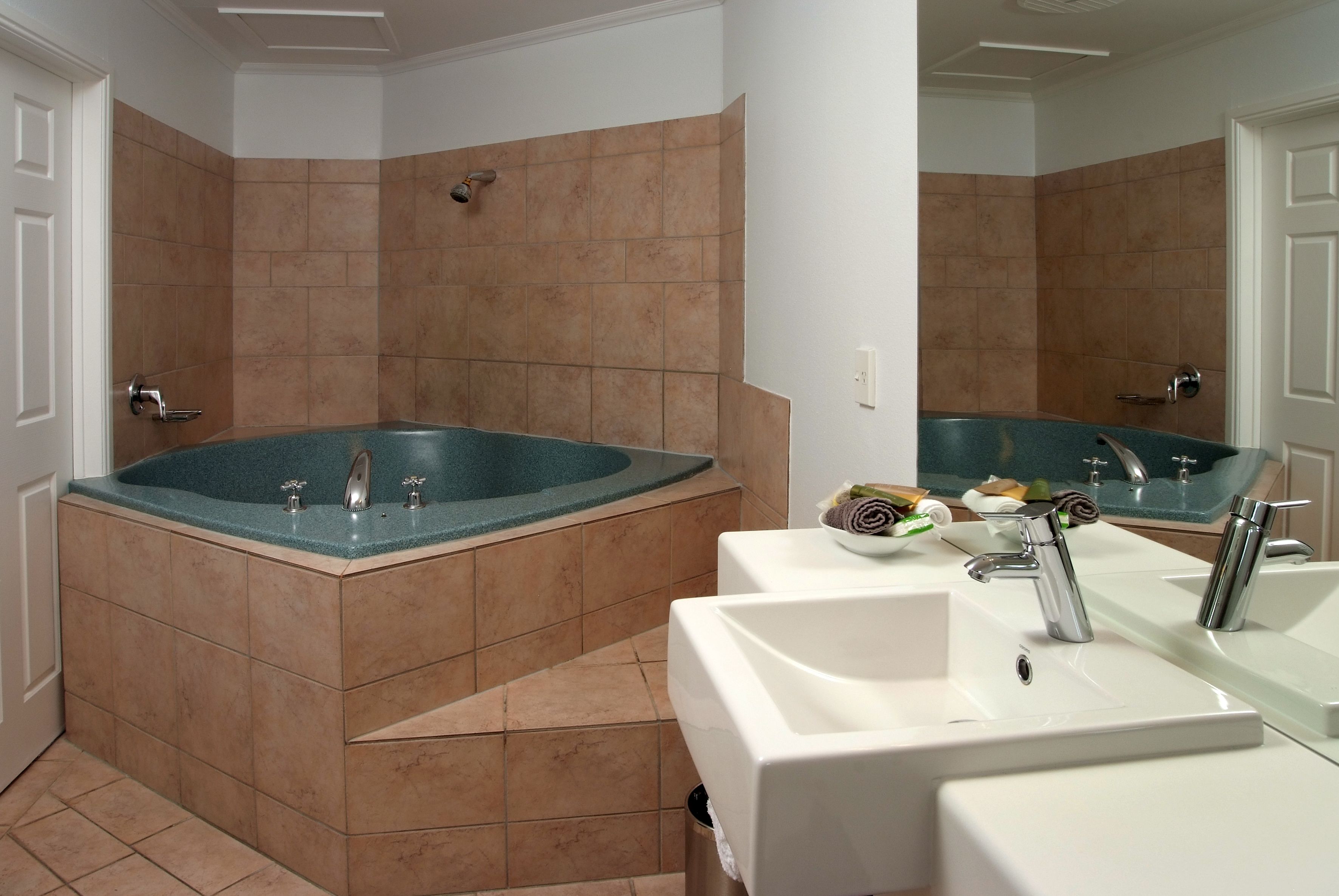 A bathroom with a large bathtub, two sinks, and a mirror.
