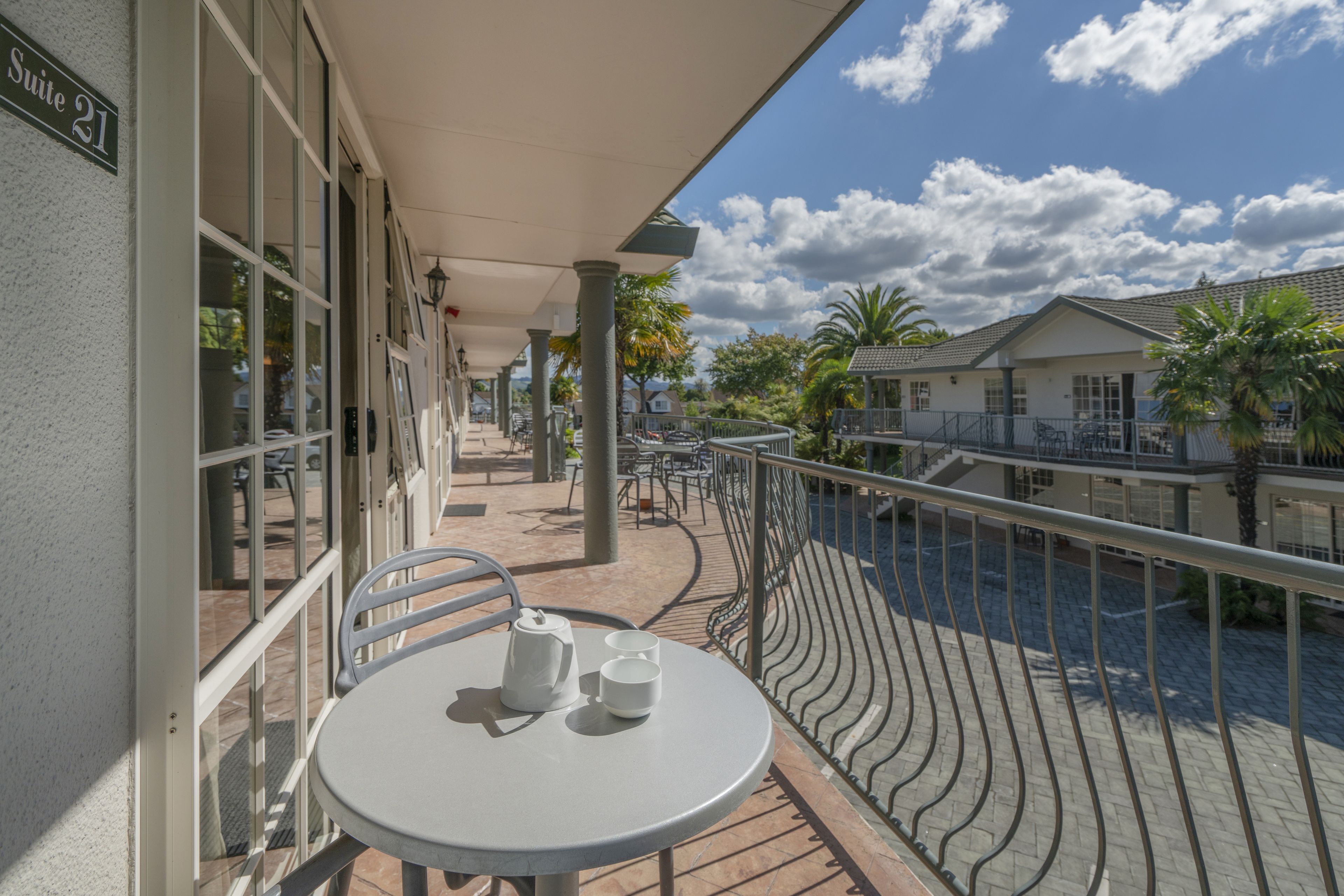 A balcony with a table and chairs, a railing, and a view of a canal and buildings.