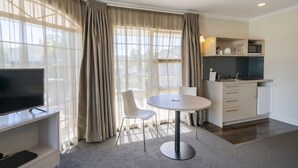 Ein modernes Zimmer mit Esstisch, Stühlen, Fernseher und Küchenzeile.