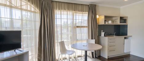 Une chambre moderne équipée d’une table à manger, de chaises, d’un téléviseur et d’une kitchenette.
