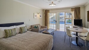 Ein Hotelzimmer mit einem großen Bett, einer Sitzecke, einem Esstisch und einem Fernseher.