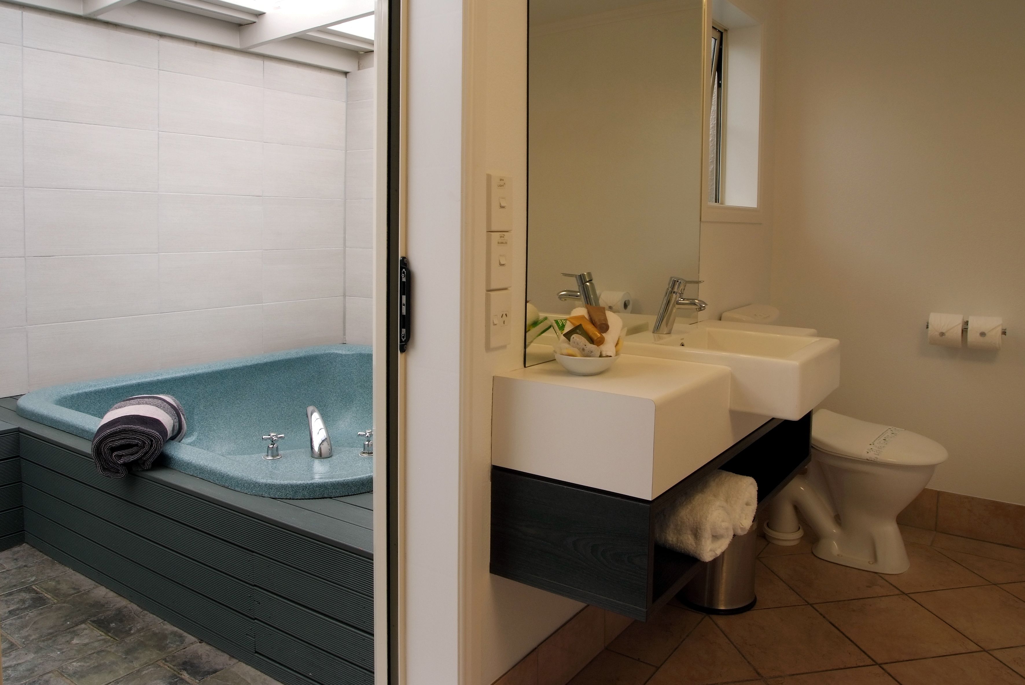 A modern bathroom with a bathtub, two sinks, and a toilet.
