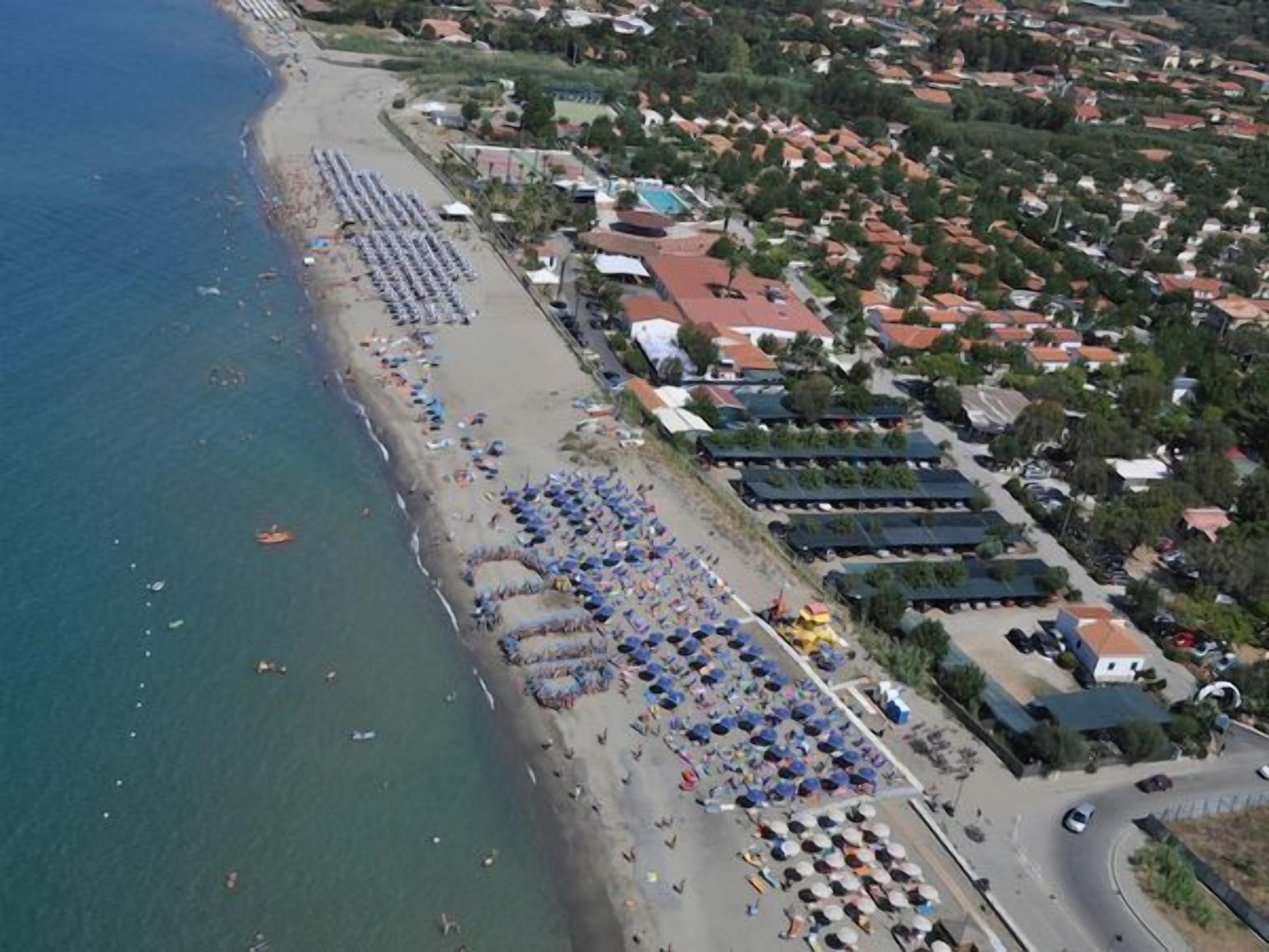 Vista aérea de una playa con hileras de sombrillas y gente disfrutando.