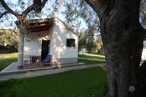A small white building with a porch, a bench, and a blue chair.