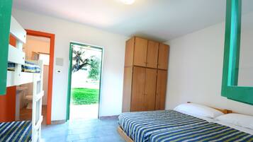 A bedroom with two beds, a wooden wardrobe, and a bathroom visible through an open door.