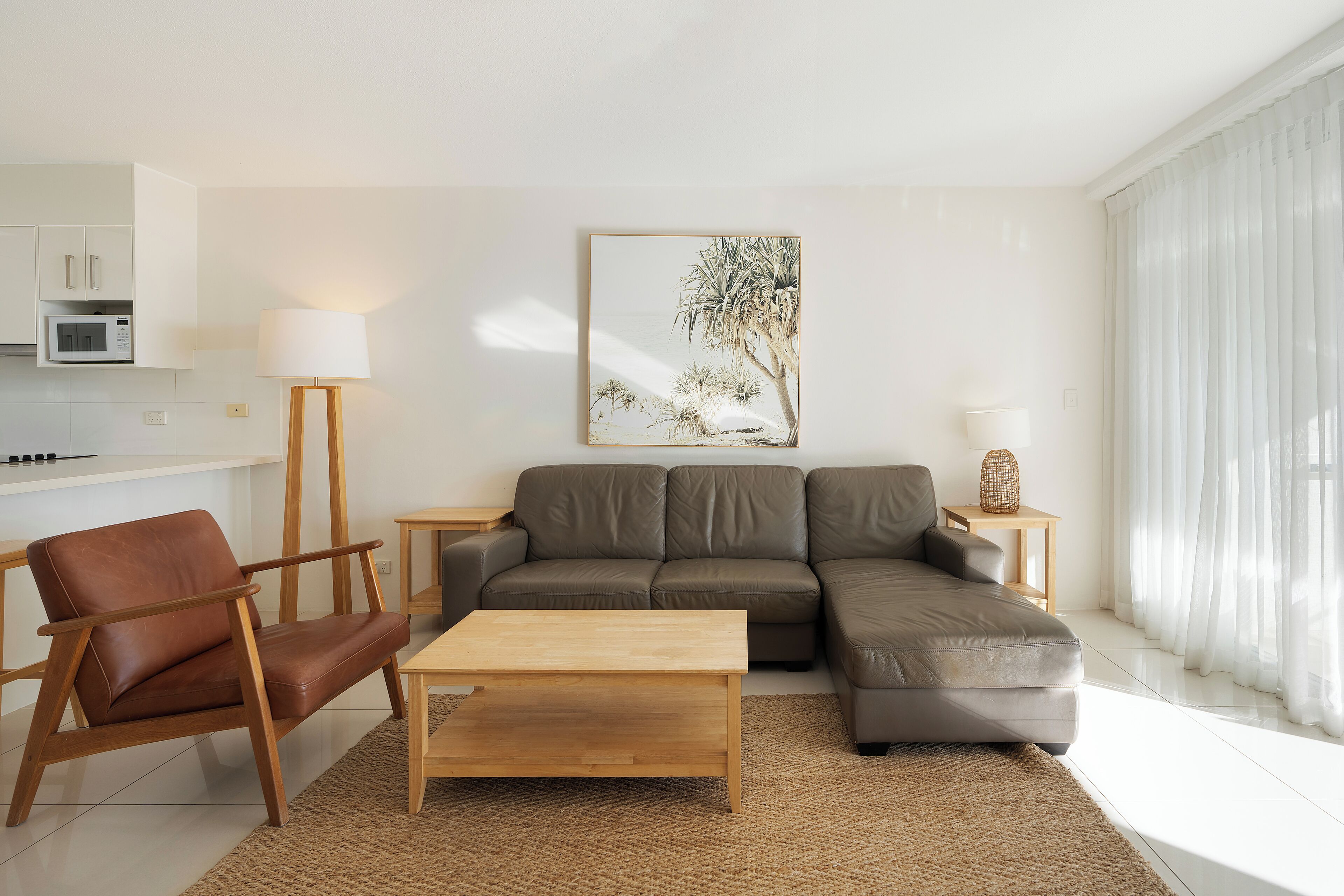 A modern living room with a brown leather sofa, a wooden coffee table, and a brown rug.