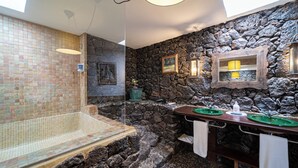 Un baño con pared de mosaicos, pared de piedra y lavamanos con encimera verde.