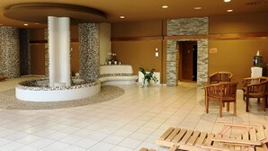 A lobby with a circular seating area, a water dispenser, and a reception desk. - Hotel Jana (Prerov)