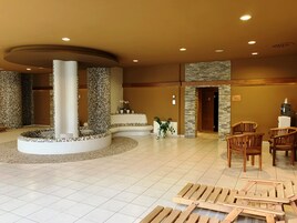 Un hall con una zona de estar circular, un dispensador de agua y una recepción.