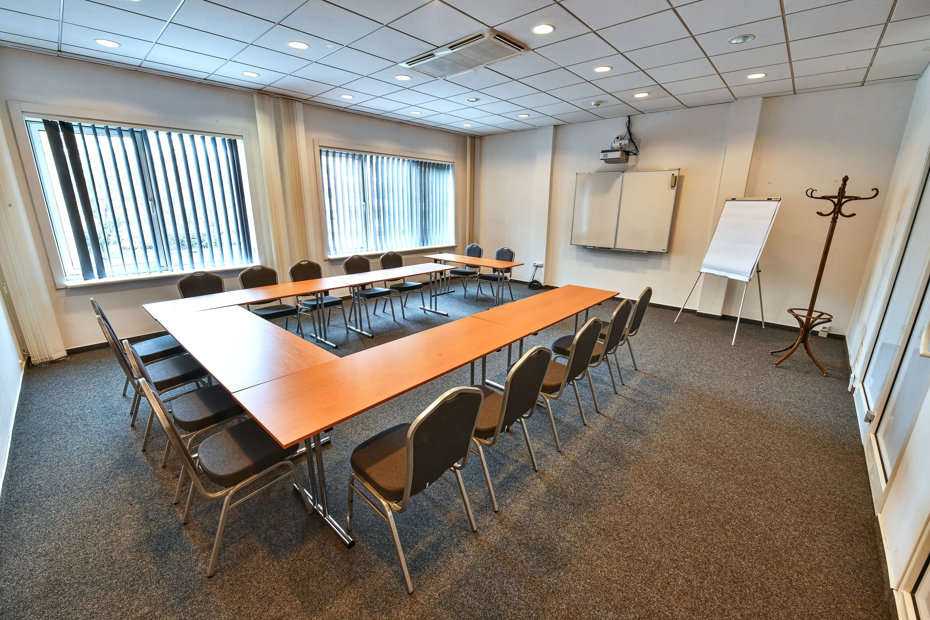 Une salle de conférence équipée d’une longue table, de chaises, d’un tableau blanc et d’un écran de projection.