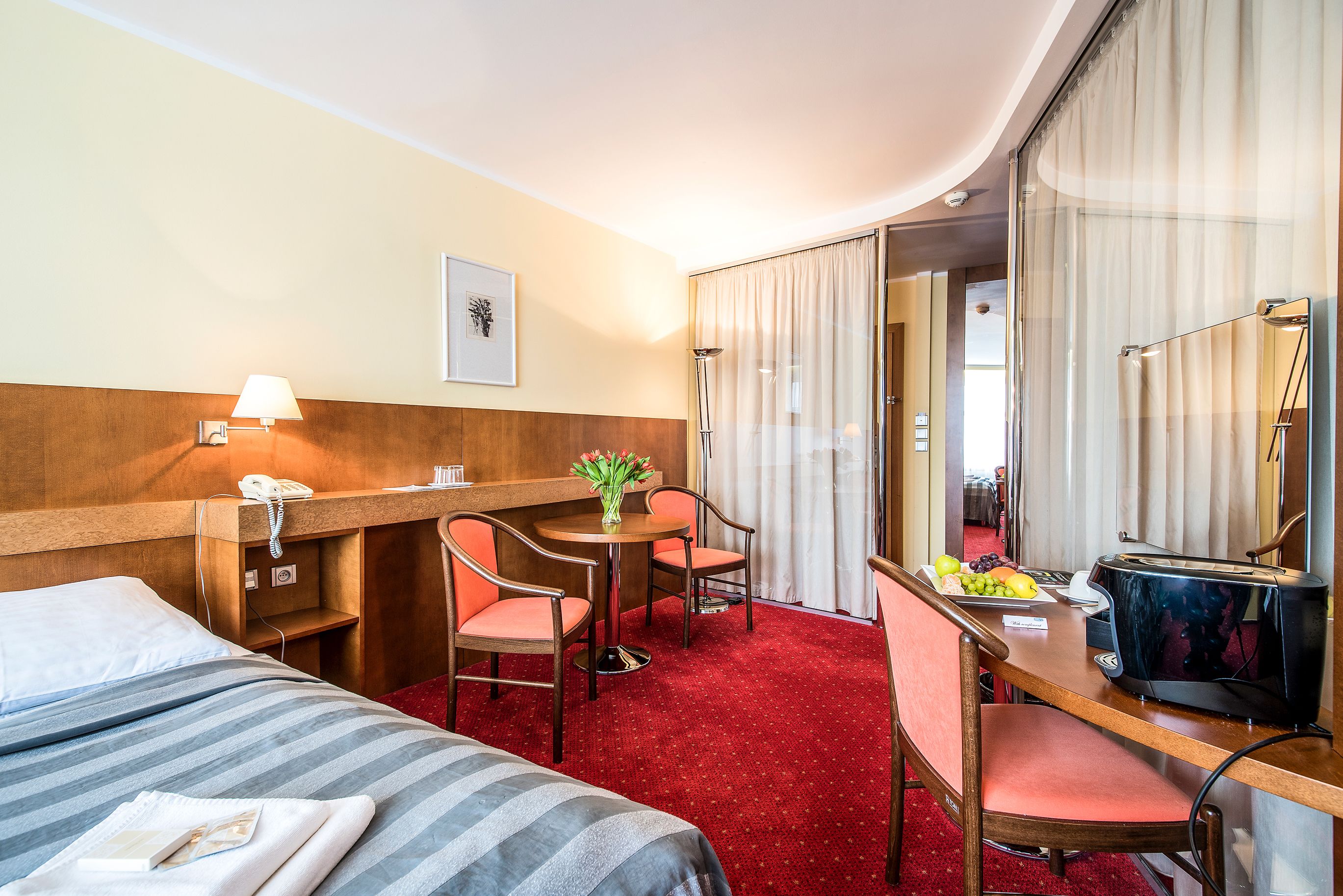 Habitació d'hotel amb un llit, escriptori amb cadira, telèfon, làmpada i mirall.