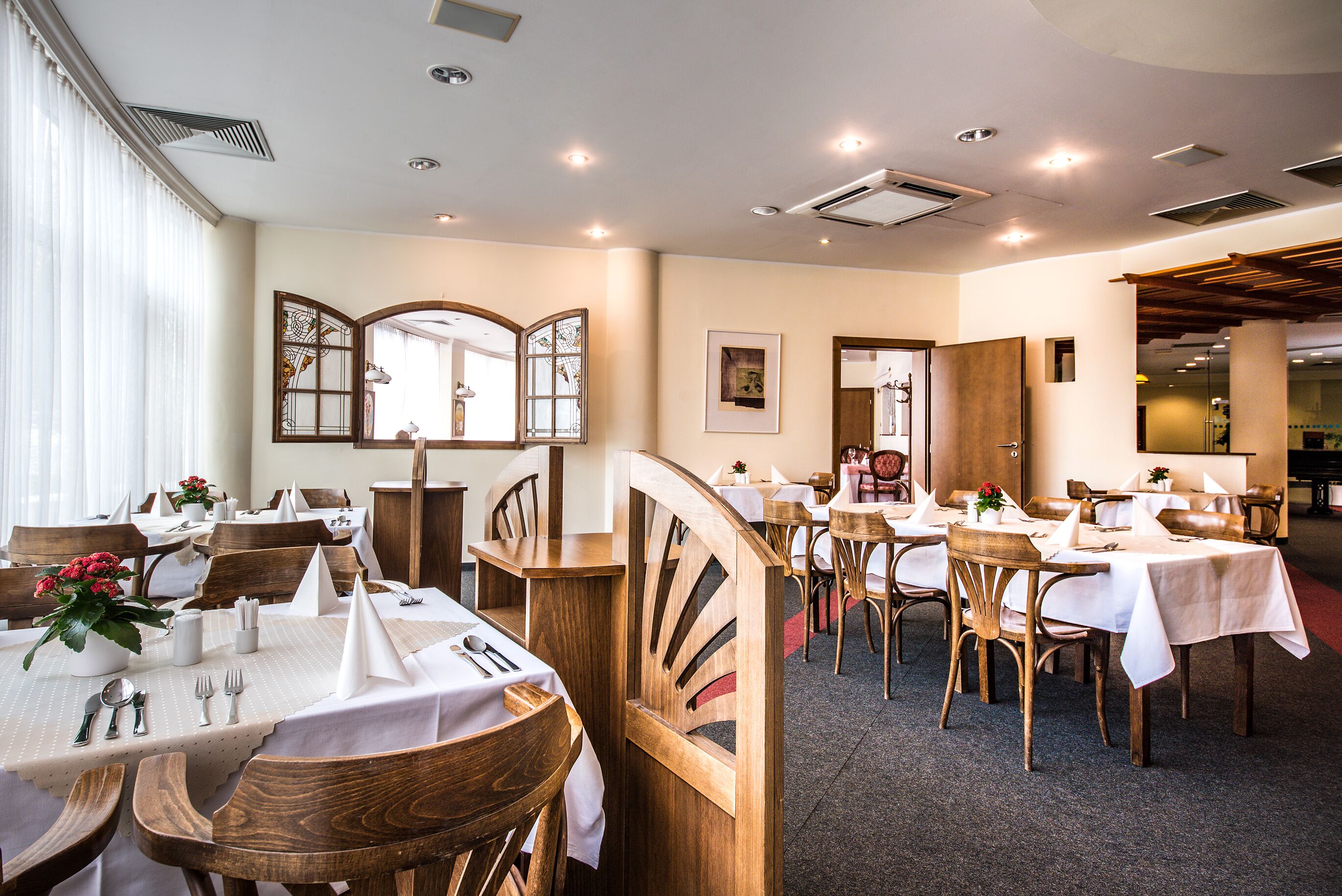 A restaurant with wooden furniture, white tablecloths, and a view of the interior.