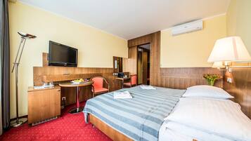 Ein Hotelzimmer mit Bett, Schreibtisch, Stuhl, Fernseher und Lampe.
