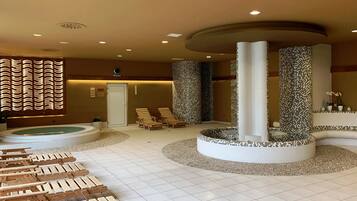 A spa area with a hot tub, wooden loungers, and mosaic pillars.