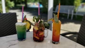 Three drinks on a table with wicker chairs around.