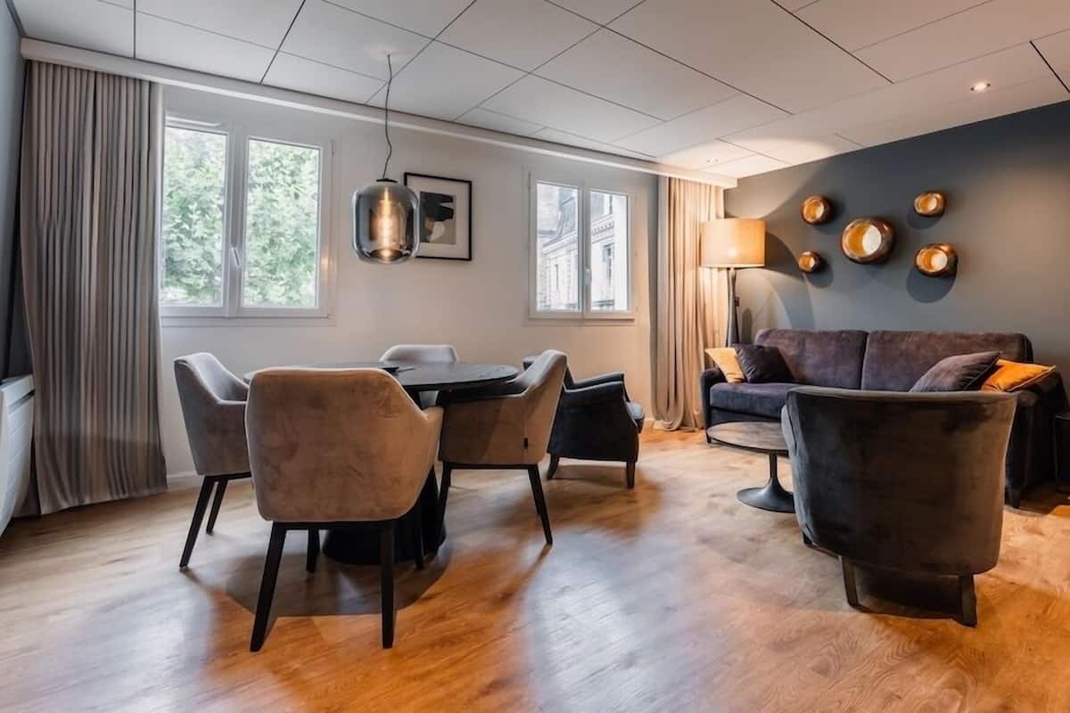 A modern living room with a dining area, a sofa, and a lamp.