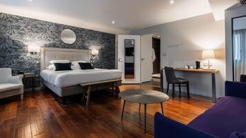 Een moderne hotelkamer met een groot bed, een bureau, een stoel en een klein tafeltje.