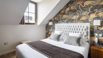 Una camera da letto con un letto grande, una finestra e un muro con carta da parati tropicale.