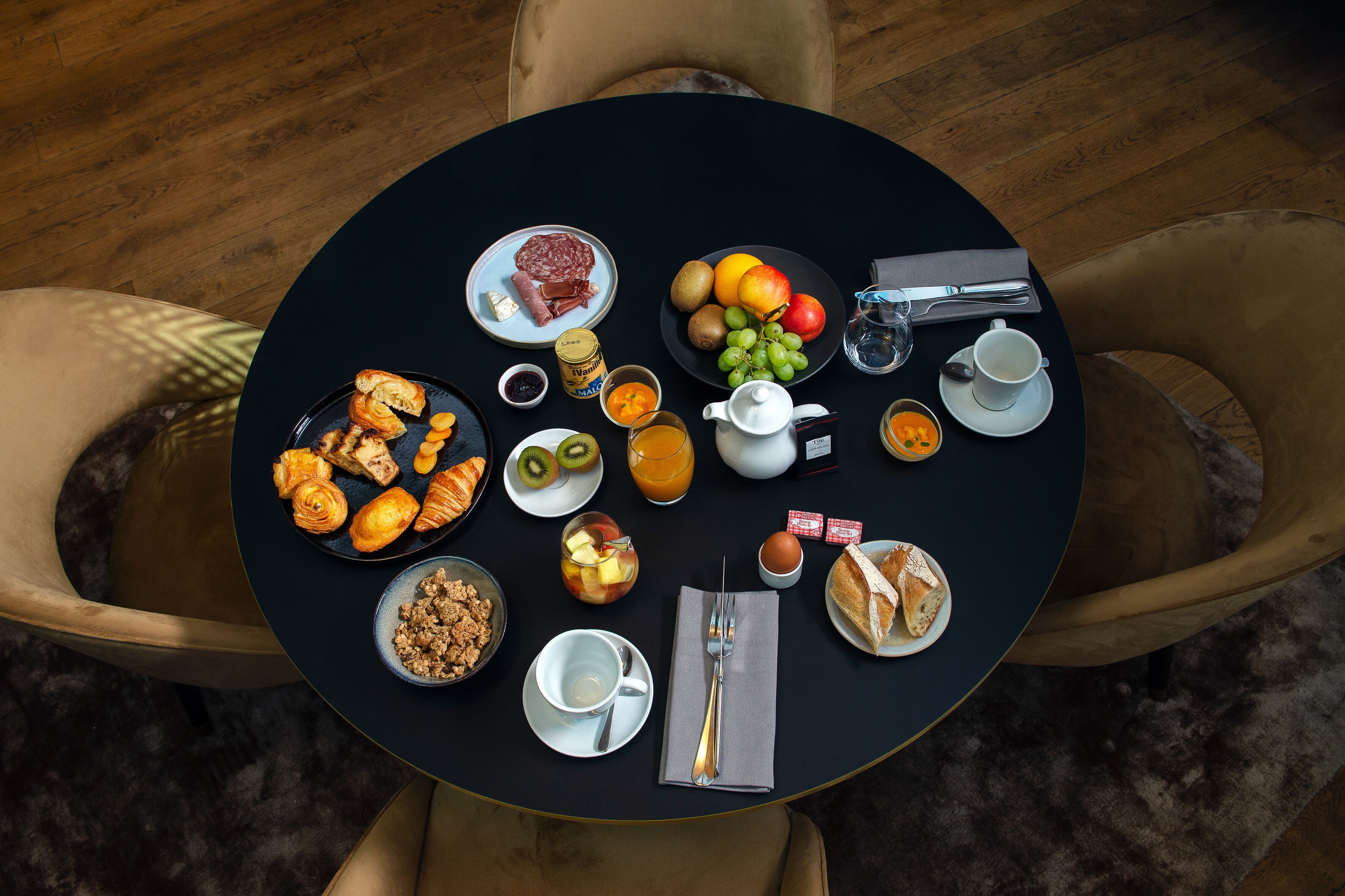 A round table with breakfast items including croissants, fruit, and coffee.