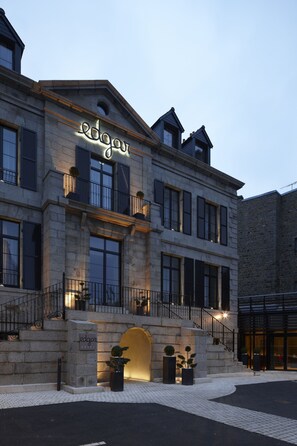 Un bâtiment à la façade en pierre, doté de grandes fenêtres et d’une enseigne sur laquelle on peut lire « edgar ».