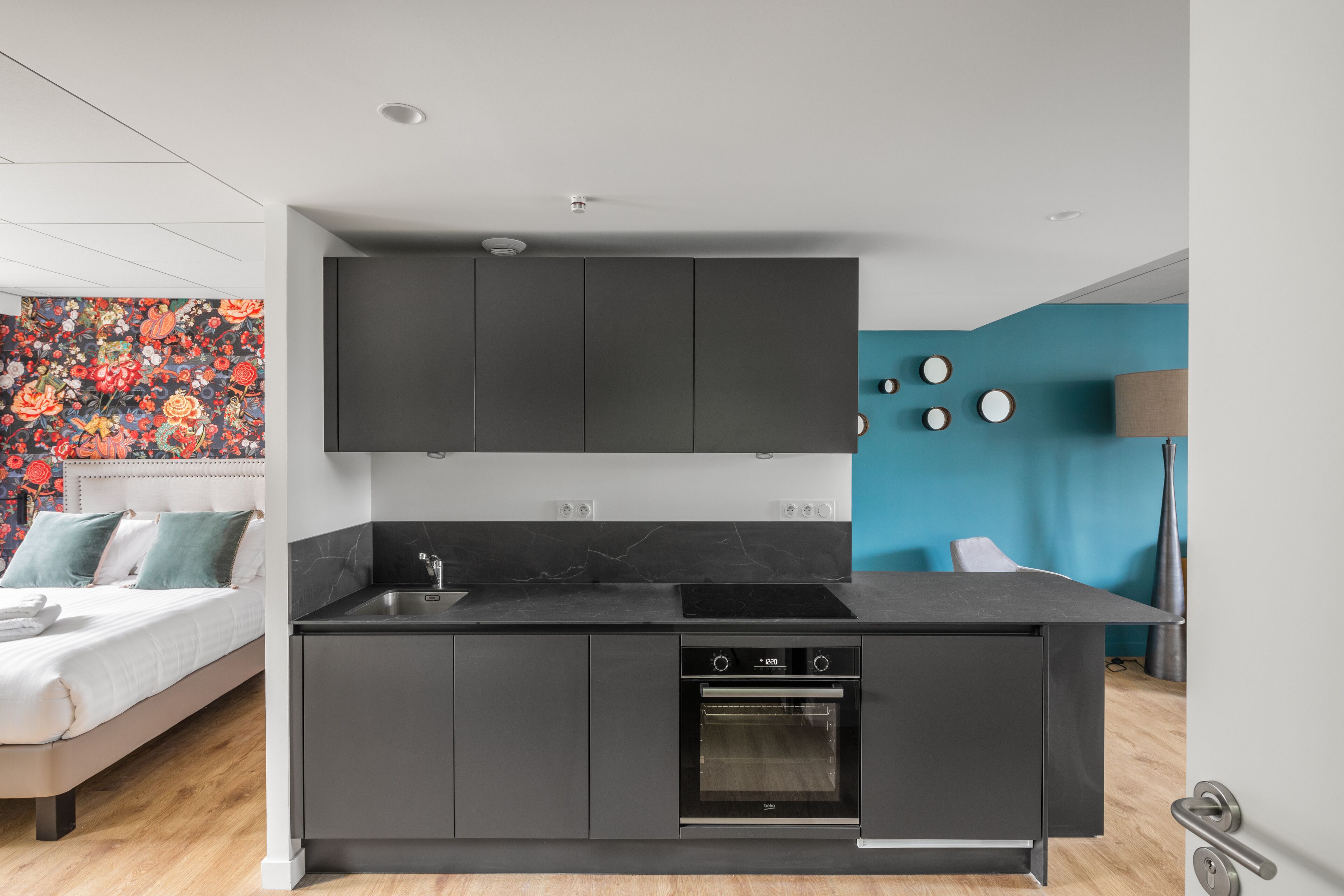 Una cocina moderna con horno empotrado, armarios oscuros y una pared azul de acento.